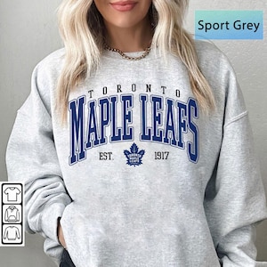 May include: Sport grey sweatshirt with navy blue "TORONTO MAPLE LEAFS" text, a maple leaf logo, and the year "1917". The sweatshirt has a crew neck and long sleeves.