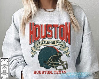 Könnte beinhalten: Hellgraues Sweatshirt mit einem verblichenen rot-weißen Aufdruck mit der Aufschrift "HOUSTON ESTABLISHED 2002" über einem türkisfarbenen Footballhelm. Darunter steht "HOUSTON, TEXAS".