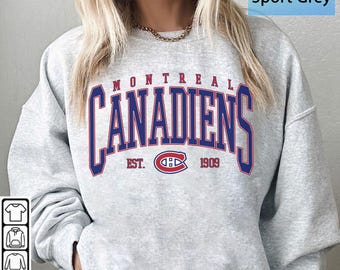 Puede incluir: Sudadera Sport Grey con el logotipo de los Canadiens de Montreal en azul y rojo. La palabra "MONTREAL" está arqueada sobre el nombre del equipo. El logotipo del equipo está en el centro, con "EST. 1909" debajo. Un diseño clásico para los fanáticos del hockey.