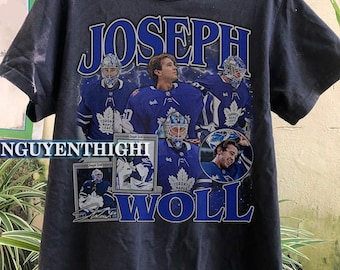 Puede incluir: Camiseta negra con un estampado gráfico del jugador de hockey Joseph Woll. El gráfico es un collage de fotos de Woll con un jersey de los Toronto Maple Leafs, incluida una foto de él sosteniendo la Copa Stanley. El texto "Joseph Woll" está impreso en letras grandes y negritas en la parte inferior del gráfico.