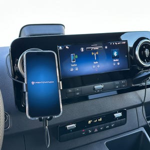 K&ouml;nnte beinhalten: Ein Smartphone, das in einem Auto montiert ist und das Logo "PRINTIVATECH" anzeigt. Das Telefon ist mit einem Ladekabel verbunden. Das Armaturenbrett des Autos verf&uuml;gt &uuml;ber ein digitales Display mit Radio- und Bluetooth-Optionen.