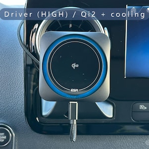 K&ouml;nnte beinhalten: Ein schwarzes und graues Qi2-Wireless-Ladeger&auml;t mit blauem Ring, montiert in der L&uuml;ftungs&ouml;ffnung des Armaturenbretts eines Autos. Das Ladeger&auml;t hat das ESR-Logo und ein Ladekabel. Der Bildschirm des Autos zeigt ein Telefonsymbol und das Wort "Telefon".