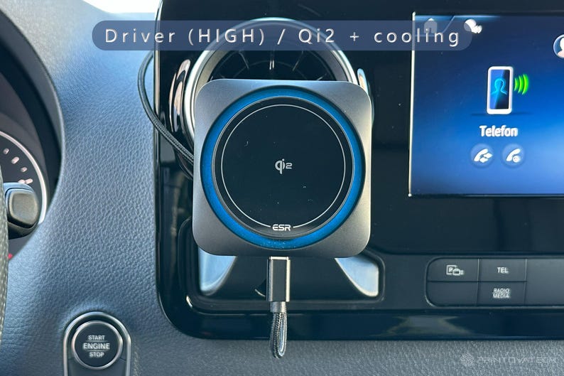 K&ouml;nnte beinhalten: Ein schwarzes und graues Qi2-Wireless-Ladeger&auml;t mit blauem Ring, montiert in der L&uuml;ftungs&ouml;ffnung des Armaturenbretts eines Autos. Das Ladeger&auml;t hat das ESR-Logo und ein Ladekabel. Der Bildschirm des Autos zeigt ein Telefonsymbol und das Wort "Telefon".