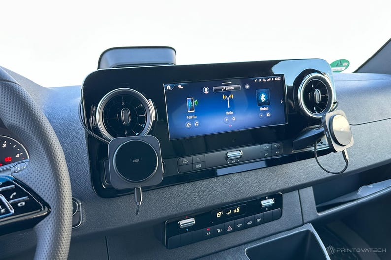 K&ouml;nnte beinhalten: Ein Armaturenbrett mit einem zentralen Bildschirm, der Telefon-, Radio- und Bluetooth-Symbole anzeigt. Bel&uuml;ftungs&ouml;ffnungen befinden sich auf beiden Seiten des Bildschirms. Ein kabelloses Ladepad ist angebracht. Die Temperaturanzeige zeigt 19 Grad Celsius an.