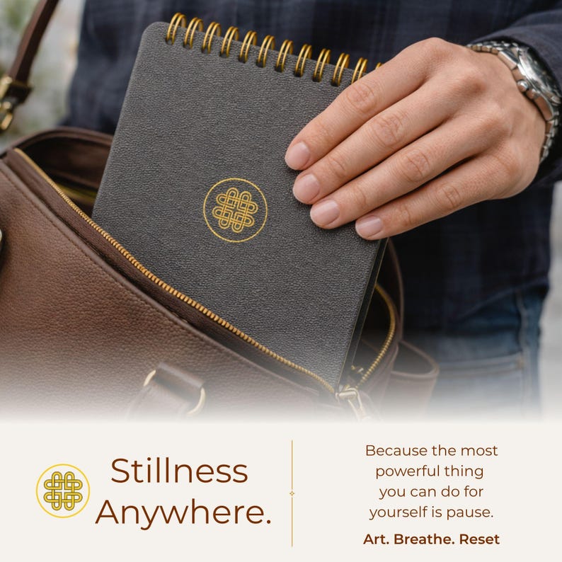 Puede incluir: Un cuaderno de espiral gris oscuro con un emblema de nudo circular dorado en la portada. El texto en la imagen dice: Stillness Anywhere. Because the most powerful thing you can do for yourself is pause. Art. Breathe. Reset.