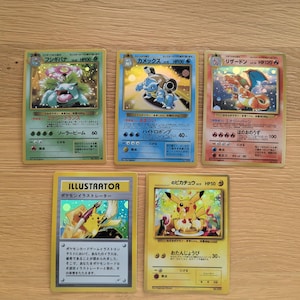Könnte beinhalten: Fünf Vintage Pokémon-Sammelkarten werden gezeigt. Die Karten zeigen verschiedene Pokémon-Charaktere, darunter Venusaur, Blastoise, Charizard und Pikachu. Die Karten sind auf Japanisch und Englisch, mit leuchtenden Farben und detaillierten Illustrationen.
