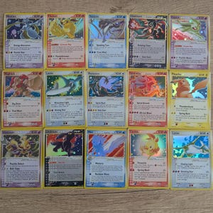 Könnte beinhalten: Eine Sammlung von fünfzehn Pokémon-Sammelkarten mit verschiedenen Charakteren und Designs. Die Karten haben einen gelben Rand und zeigen Bilder von Kreaturen wie Mewtwo, Flareon und Charizard. Jede Karte zeigt Charakternamen, KP und Angriffsdetails.
