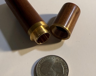 May include: A wooden container with a brass fitting, shown open with the lid next to the body. The container is dark brown with a polished finish. A US quarter is next to the container for size comparison.