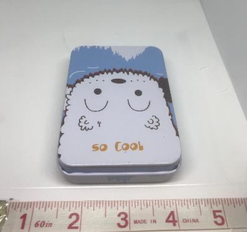 Puede incluir: Una lata azul y blanca con una ilustraci&oacute;n de dibujos animados de un perro blanco con el texto "so cool" en la parte delantera.
