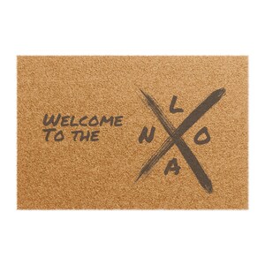 May include: Welcome to the LA doormat with a brown coir surface and black lettering. The text reads "Welcome to the LA" with a stylized "LA" logo.