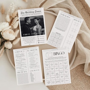 May include: A set of four white wedding activity cards featuring black text and graphics. One card displays a newspaper-style layout titled The Wedding Times with a photo of a couple, while others include word search, sudoku, bingo, and trivia games.