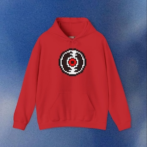 Peut inclure: Un sweat à capuche rouge avec un motif de disque vinyle pixélisé sur le devant. Le graphisme présente un anneau extérieur noir et blanc avec un centre rouge. Le sweat à capuche a une poche kangourou et une capuche à cordon.