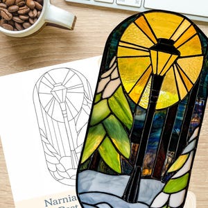 Könnte beinhalten: Ein Lampenpfosten-Design aus Buntglas mit einer gelben Lampe, grünen Blättern und einem blauen Sockel. Das Design ist schwarz gerahmt und hat einen weißen Hintergrund. Der Text "glass sanctuary" befindet sich in der unteren rechten Ecke.