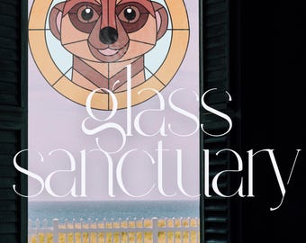 May include: A stained glass window with a meerkat design. The window is set in a wooden frame with white shutters. The text "glass sanctuary" is written below the window.