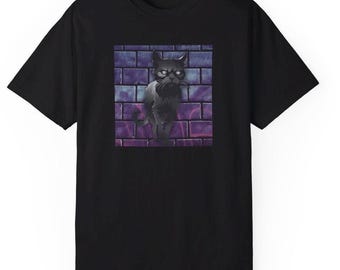 以下が含まれることがあります： 紫と青のアクセントのあるレンガの壁の前に眼鏡をかけた黒い猫のグラフィックがプリントされた黒いTシャツです。