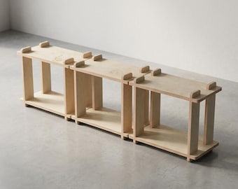 Könnte beinhalten: Ein modulares Regal aus hellem Holz mit drei miteinander verbundenen quadratischen Fächern. Das Design verwendet eine Steckverbindung mit sichtbaren Verbindungsstellen an den Ecken, wodurch eine niedrige Aufbewahrungsstruktur entsteht.