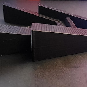 May include: A black plastic laptop stand with three tiers, designed to elevate a laptop for better ergonomics.