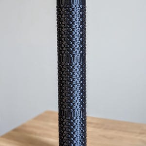 May include: A black foam roller with a textured surface. The roller is designed for muscle recovery and stretching.