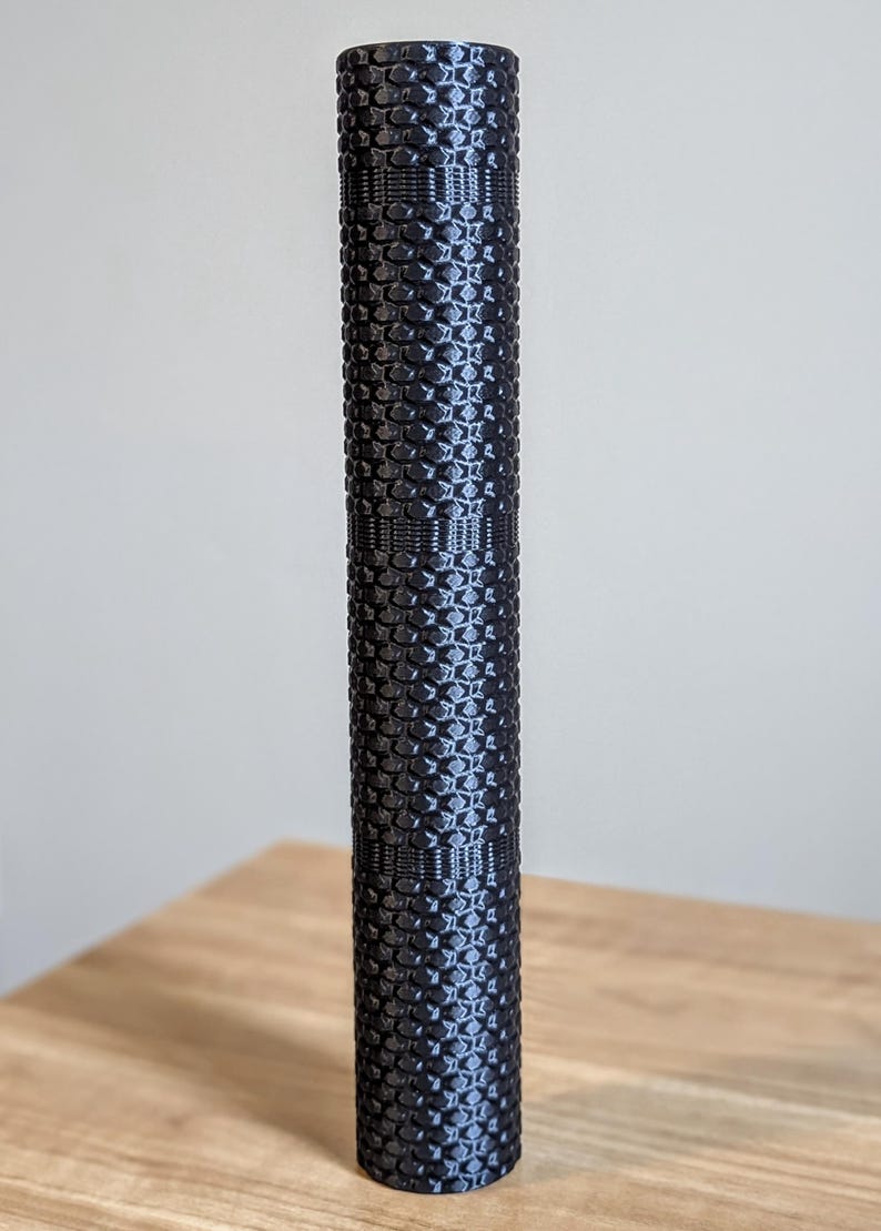 May include: A black foam roller with a textured surface. The roller is designed for muscle recovery and stretching.