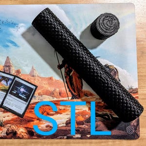 May include: Black foam tube with a textured surface and a black foam circle. The tube is lying on a brown and orange patterned surface with the word "STL" printed in blue.