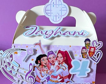 May include: A white party favor box with a handle, featuring a cartoon illustration of three girls, musical notes, and the name "Jayhani". The number "24" is also visible.