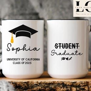 Puede incluir: Dos tazas de cerámica blanca con asas negras y bordes negros. La taza de la izquierda tiene un gorro de graduación negro con una borla dorada y el texto "Sophia, University of California, Class of 2025". La taza de la derecha tiene el texto "Student Graduate" con un gorro de graduación, un corazón y un gráfico de llave.