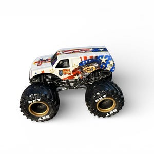 May include: A white monster truck toy with patriotic graphics, including stars, stripes, and an Uncle Sam character. The truck has large black tires with gold rims and the text "BKT". The truck's design incorporates red, white, and blue colors.