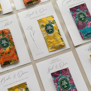 May include: Arrangement of white cards with elegant calligraphy and small packets of refreshing towels. The packets feature colorful floral and citrus designs with the text "EYÜP SABRI TUNCER 1923". Some cards include dates and names.