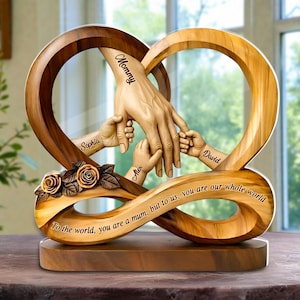 Puede incluir: Escultura de madera en forma de corazón con manos entrelazadas, con los nombres "Mommy", "Sophia", "Alex" y "David". La escultura incluye la cita "To the world, you are a mum, but to us, you are our whole world". Rosas decorativas talladas en la base.
