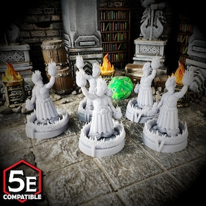 May include: A collection of grey miniature figurines depicting a humanoid figure with flames, encircled by a ring of flames. The figurines are on a stone surface, with a green die and a "5E COMPATIBLE" logo. The background features barrels and bookshelves.