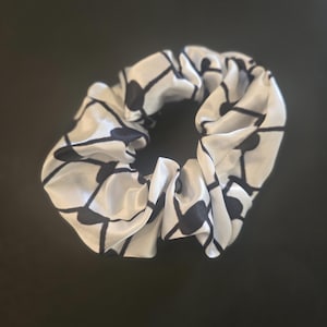 May include: White satin scrunchie with a black geometric pattern.