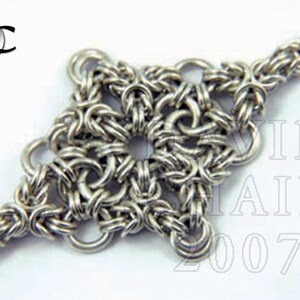 Puede incluir: Un brazalete de cadena de plata con un colgante en forma de estrella. El colgante est&aacute; hecho de anillos de metal entrelazados.