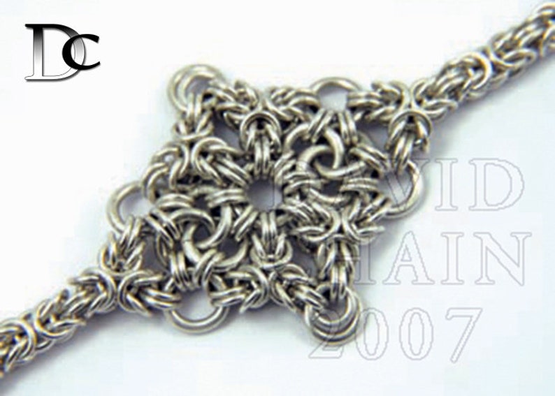 Puede incluir: Un brazalete de cadena de plata con un colgante en forma de estrella. El colgante est&aacute; hecho de anillos de metal entrelazados.