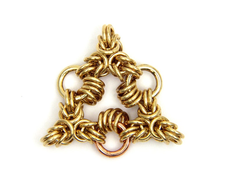 Puede incluir: Un colgante de cadena de metal de color dorado en forma de tri&aacute;ngulo. El colgante est&aacute; hecho de m&uacute;ltiples anillos entrelazados.