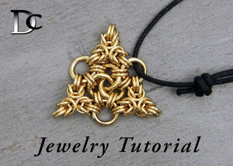 Puede incluir: Collar con colgante triangular dorado con un dise&ntilde;o de malla de cadena tejido. El collar est&aacute; en un cord&oacute;n negro con un nudo en el extremo. "Tutorial de joyer&iacute;a" est&aacute; escrito debajo del colgante.