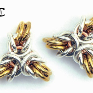 Puede incluir: Dos colgantes de nudo triquetra de metal dorado, plateado y cobre. Los nudos est&aacute;n entrelazados y forman una estrella de tres puntas.