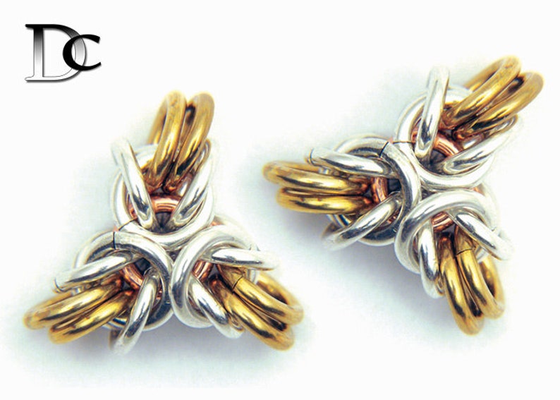 Puede incluir: Dos colgantes de nudo triquetra de metal dorado, plateado y cobre. Los nudos est&aacute;n entrelazados y forman una estrella de tres puntas.