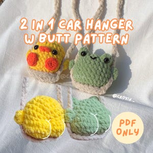 Op de afbeelding: Gehaakte auto-hangers in de vorm van een gele eend en een groene kikker, met de tekst "2 IN 1 CAR HANGER W BUTT PATTERN" en "PDF ONLY". De eend heeft rode wangen en de kikker heeft een lachend gezicht.