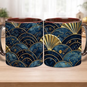 May include: Two ceramic coffee mugs with a dark brown interior and handle. The exterior features a repeating pattern of navy blue and gold fan shapes and dots. The mugs are on a wooden surface.