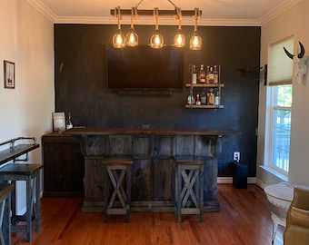 May include: A dark wood bar with two stools and a black chalkboard wall behind it. There are six light bulbs hanging from the ceiling above the bar.