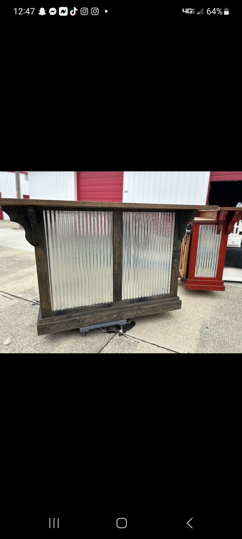 May include: A rustic wooden bar counter with a corrugated metal front. The counter has a dark wood finish and is supported by a wooden base. The metal front is silver and has a slightly distressed look.