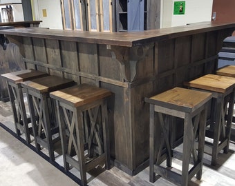 May include: A rustic wooden bar with a dark brown finish and a set of six matching bar stools. The stools have a black finish and a criss-cross design on the back.