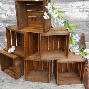May include: A set of six wooden crates stacked in a pyramid shape. The crates are made of natural wood and have a rustic, distressed look. The crates are empty and ready to be used for storage or display.