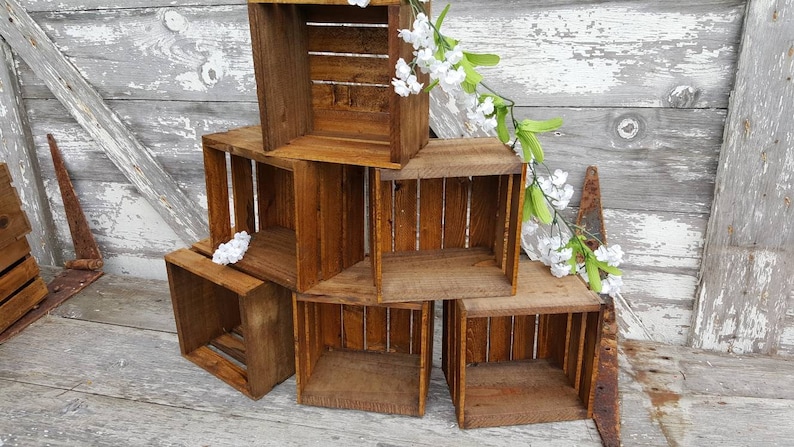 May include: A set of six wooden crates stacked in a pyramid shape. The crates are made of natural wood and have a rustic, distressed look. The crates are empty and ready to be used for storage or display.