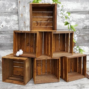 May include: A set of six wooden crates stacked in a pyramid shape. The crates are made of natural wood and have a rustic brown finish. The crates are empty and ready to be used for storage or display.