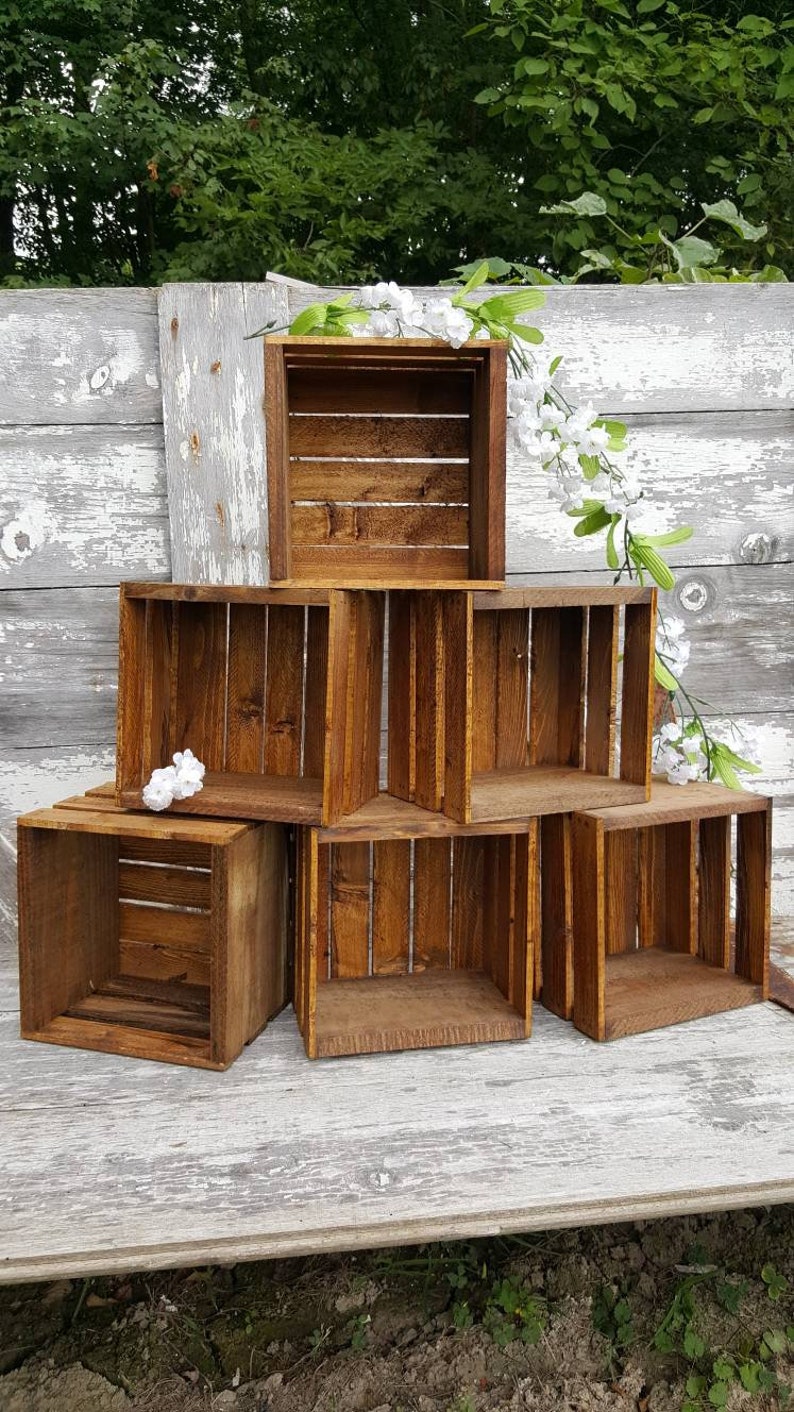 May include: A set of six wooden crates stacked in a pyramid shape. The crates are made of natural wood and have a rustic brown finish. The crates are empty and ready to be used for storage or display.