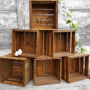 May include: A set of six wooden crates stacked in a pyramid shape. The crates are made of natural wood and have a rustic, distressed look. They are perfect for displaying small items or plants.