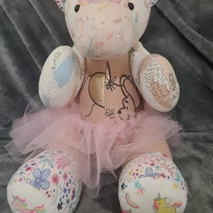 May include: A pink and white unicorn stuffed animal wearing a pink tutu. The unicorn has a pink bow on its head and is made from different fabrics with a variety of patterns.