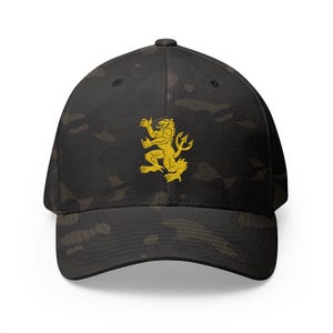May include: A black camouflage baseball cap with a gold lion emblem. The cap has a curved peak and a structured fit. The hat is made of a durable fabric.
