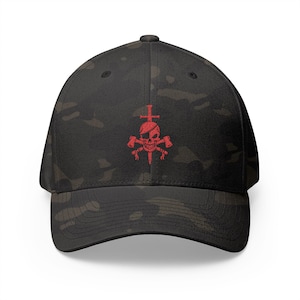 May include: Black camouflage baseball cap with a red skull and crossbones design. The skull has an eye patch and is crossed with a sword and two hammers. The cap has a curved brim and a structured fit.
